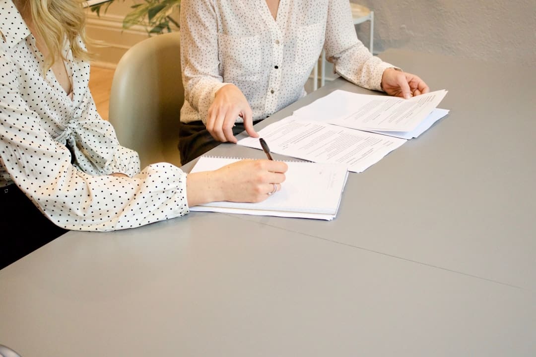 housing discrimination complaint — woman signing on white printer paper beside woman about to touch the documents